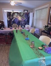 Long table with green tablecloth and enchanted forest backdrop