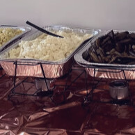 Buffet line of chafing dishes with pasta, rice and sides
