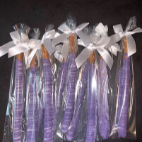 Purple chocolate-dipped pretzel rods wrapped with white bows